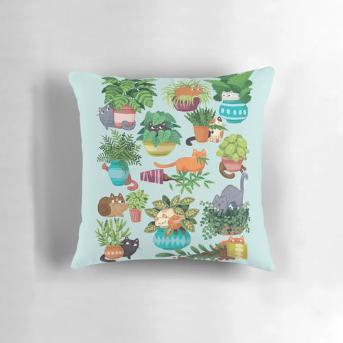 Cute black and tabby cats sitting in a variety of plants on a decorative pillow