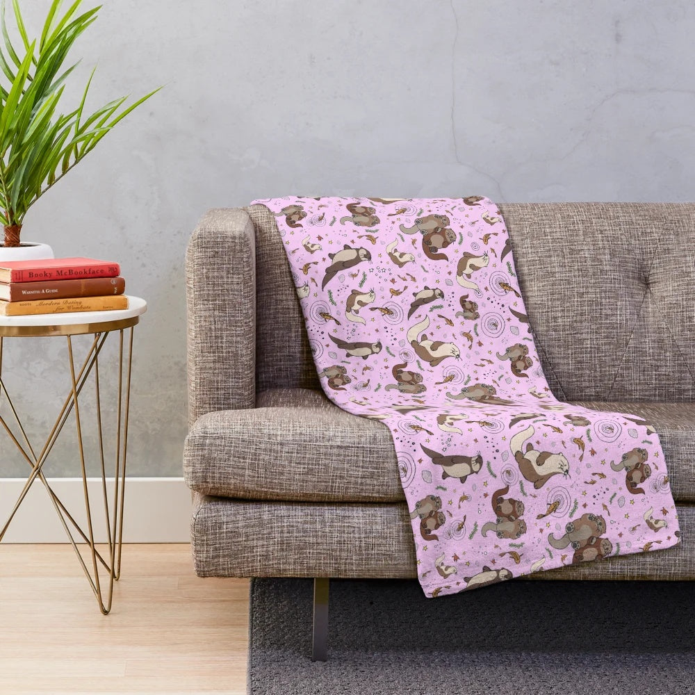 Cozy pink plush blanket featuring a cute otter design