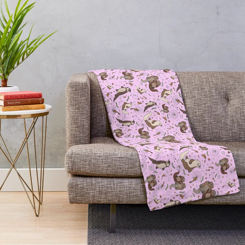 Cozy pink plush blanket featuring a cute otter design