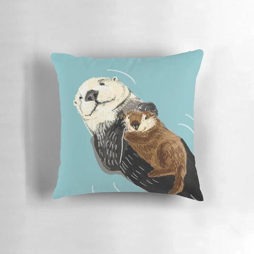 Soft, plush pillow featuring a cute sea otter mother and her baby otter snuggling on a river bank.