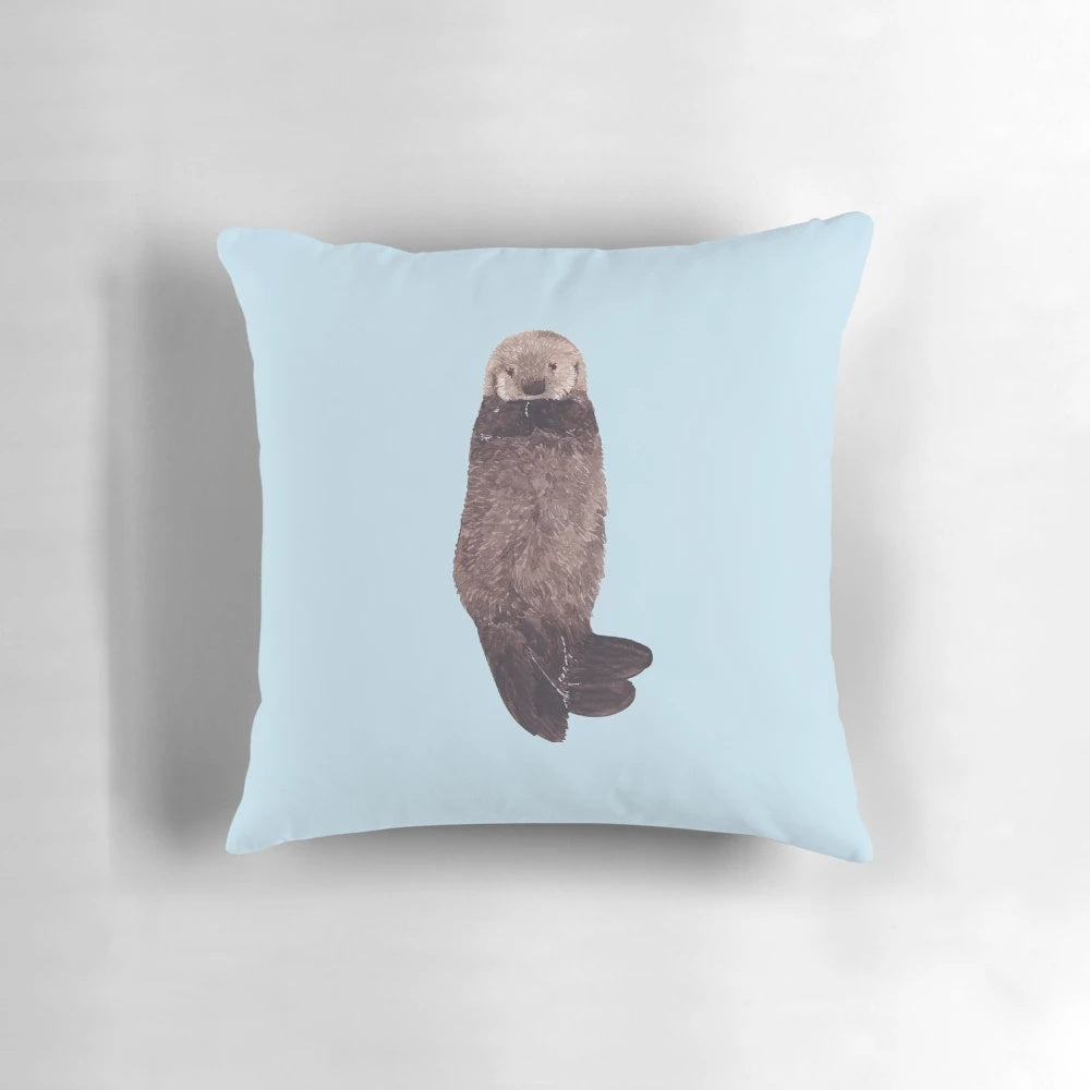 Soft, fluffy watercolor illustration of a baby sea otter on a decorative pillow