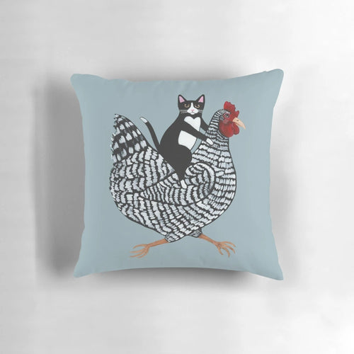 Tuxedo cat sitting on a chicken-shaped pillow, a humorous and cute home decor item.