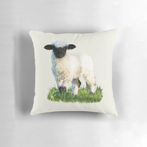 A soft, plush pillow featuring an adorable Valais Blacknose sheep lamb in a beautiful natural meadow setting.