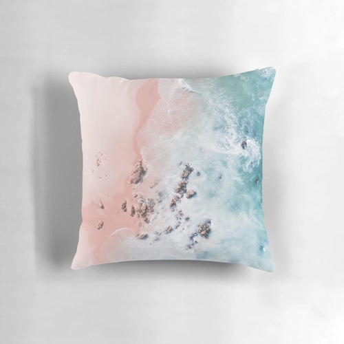 Aerial photograph of a pink sandy beach with crashing waves and a serene ocean view