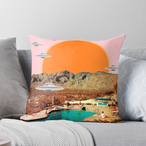 Throw pillow featuring a vibrant, photorealistic image of a UFO landing in a desert landscape with cacti and a pink sunset sky.