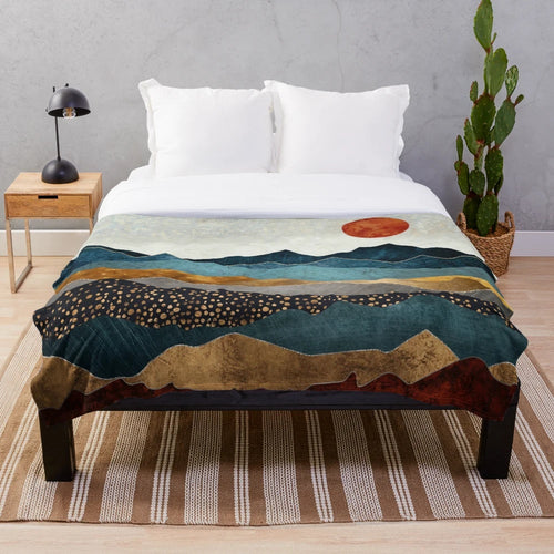 Soft and cozy amber plush blanket with a landscape design depicting a dusk sky over hills and mountains