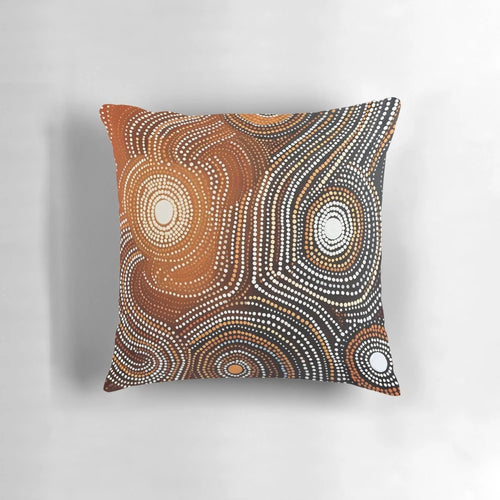Pillow featuring contemporary Aboriginal art with dots, curved lines, and earthy colors that conveys stories and spirituality.