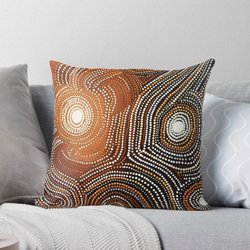 Pillow featuring contemporary Aboriginal art with dots, curved lines, and earthy colors that conveys stories and spirituality.