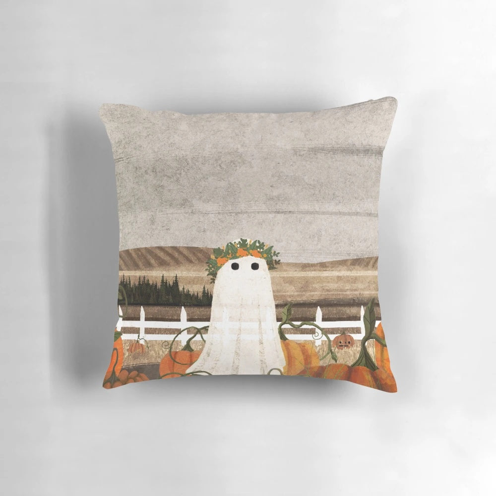 A vintage-inspired throw pillow featuring a ghostly figure in a pumpkin patch landscape.