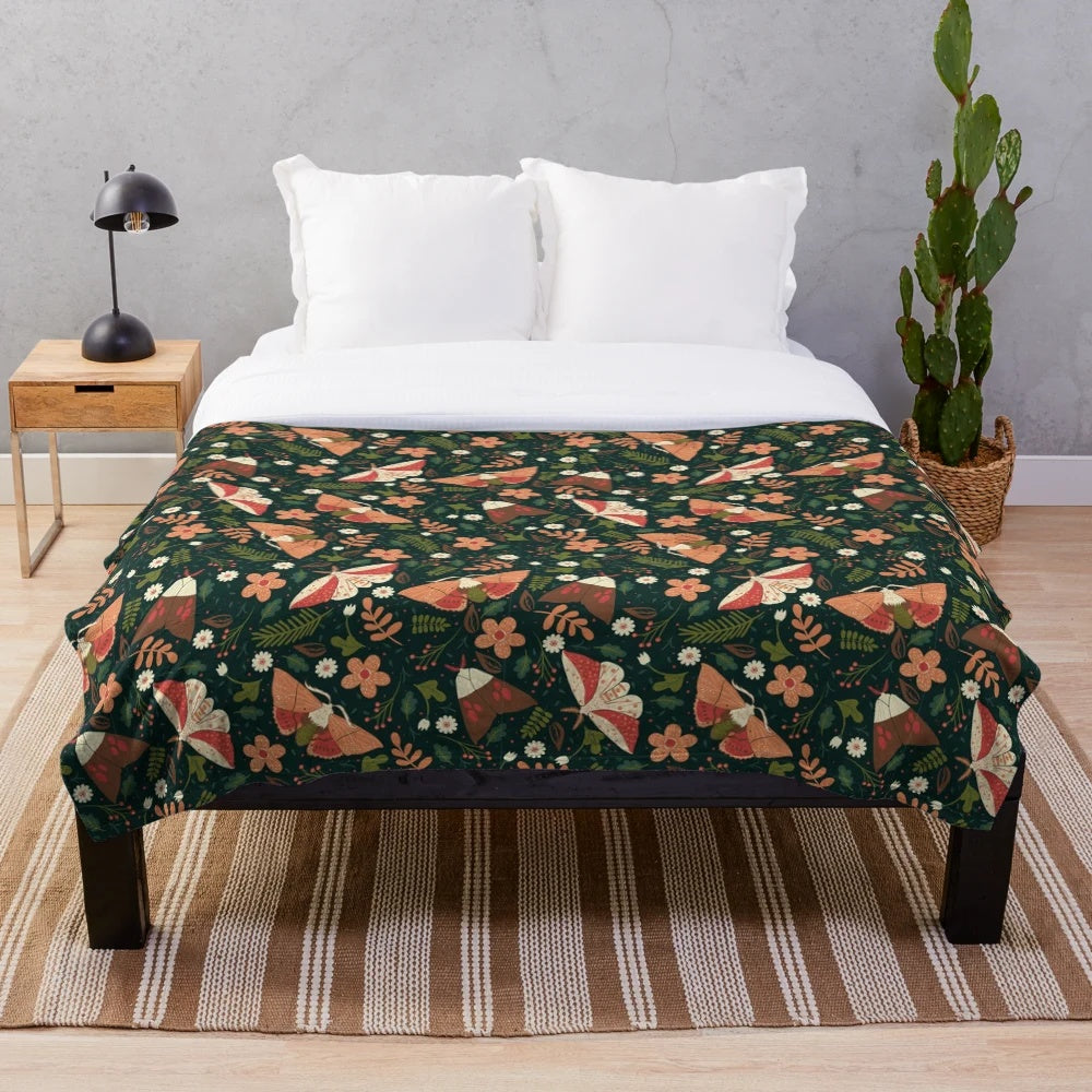 Colorful plush blanket with a pattern featuring moths, leaves, and flowers