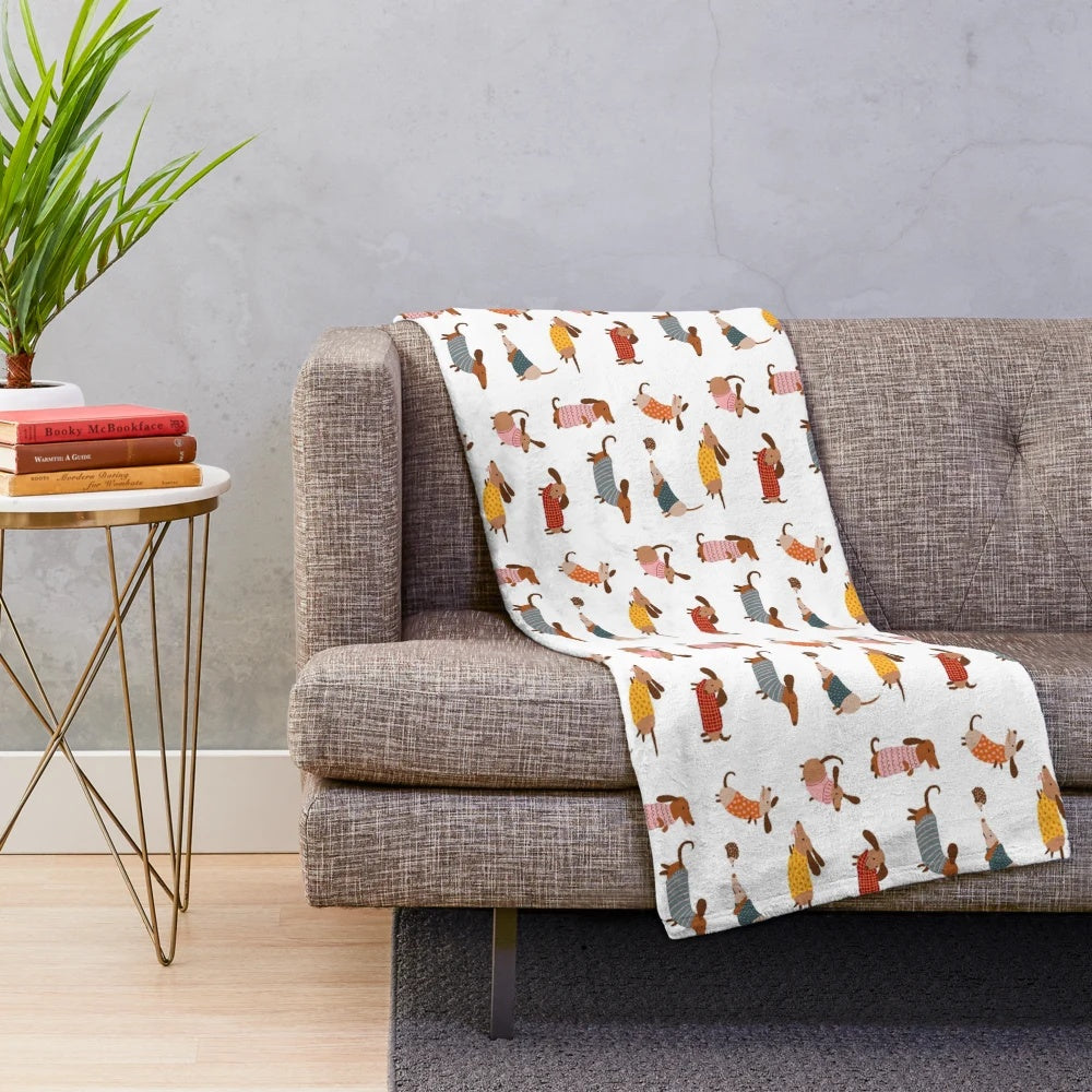 Dachshund dogs wearing winter sweaters on a plush blanket