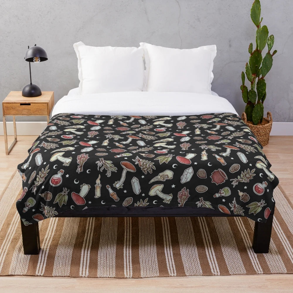 Dark plush blanket with a witchy pattern featuring moons, stars, and mushrooms