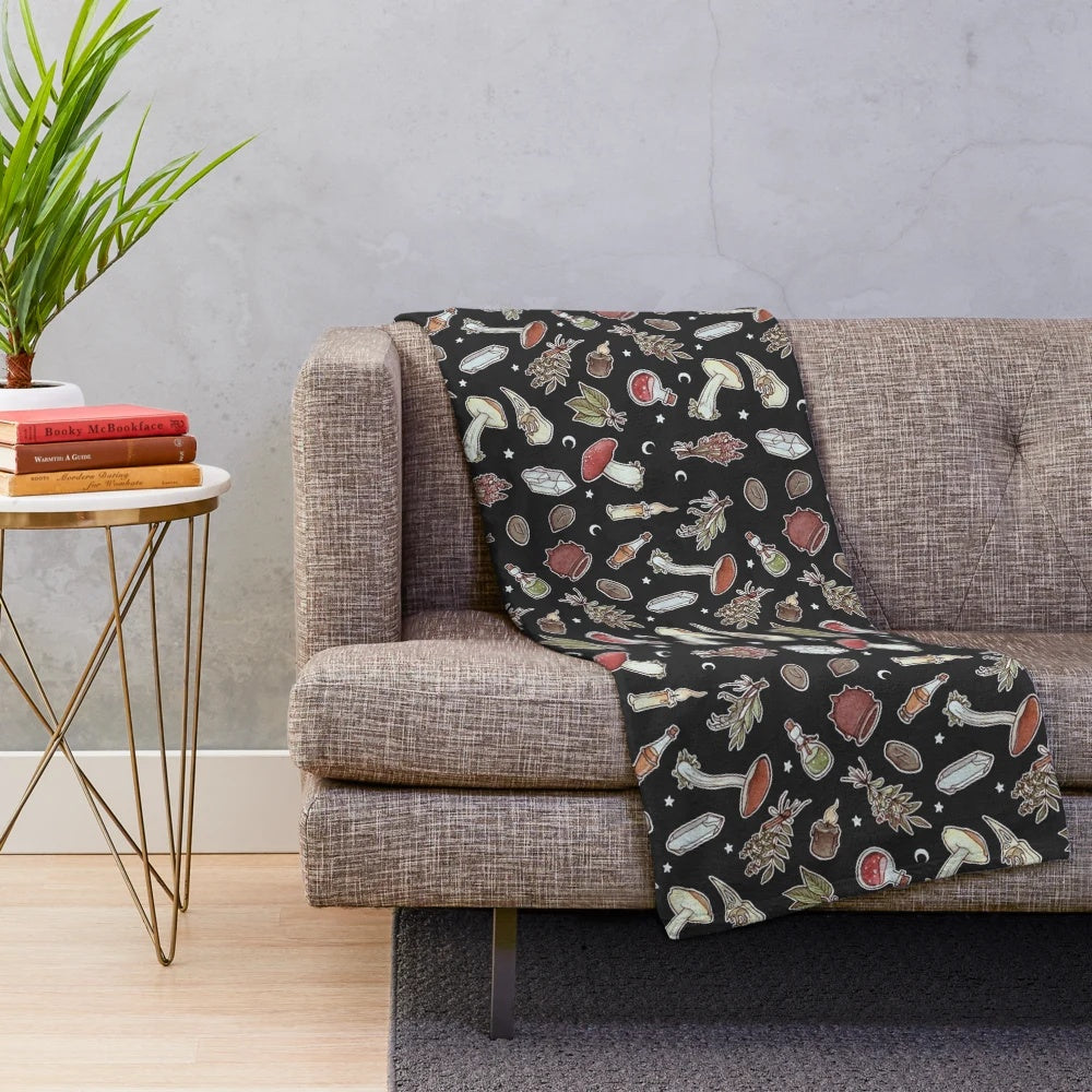 Dark plush blanket with a witchy pattern featuring moons, stars, and mushrooms