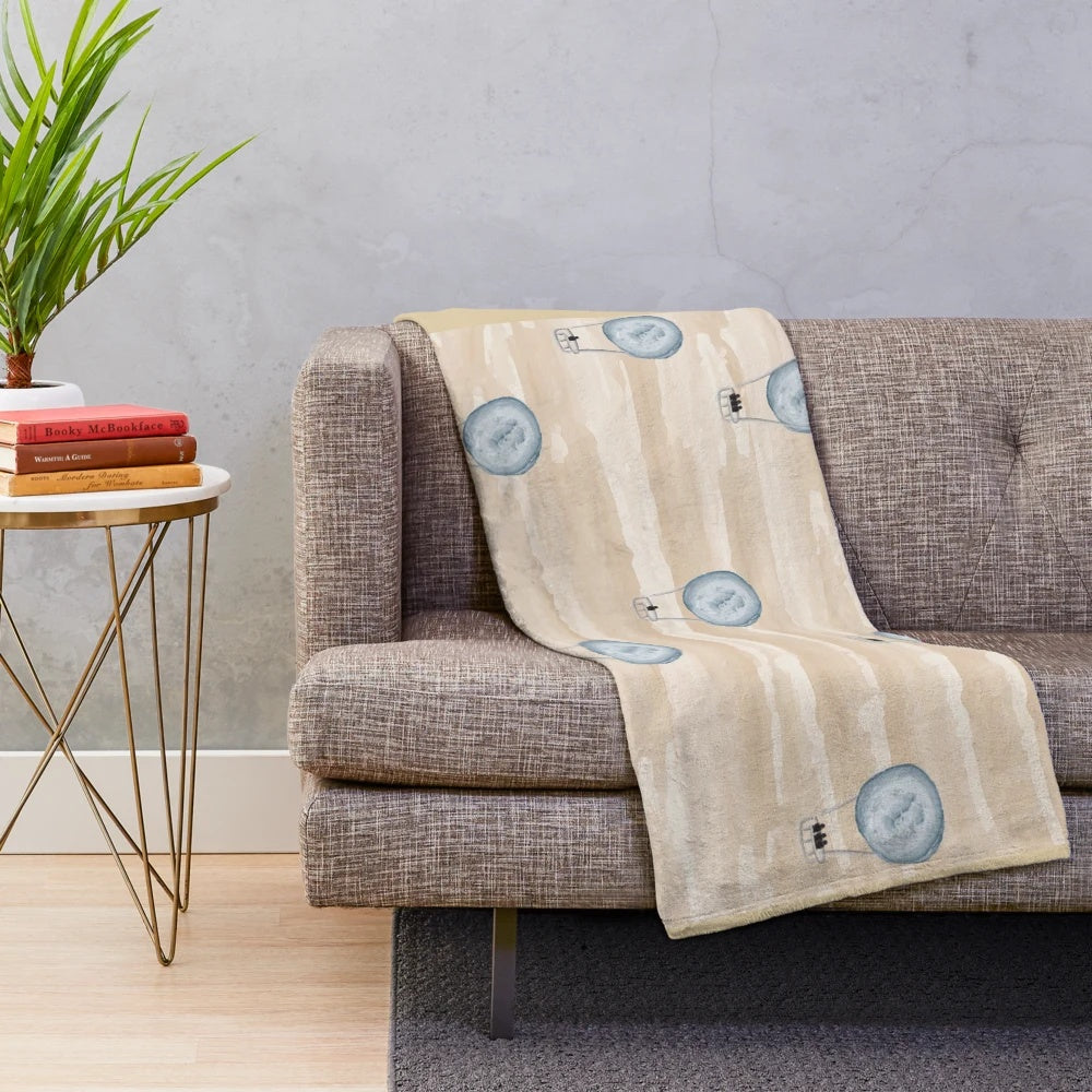 Plush blanket with a seamless pattern of air balloons floating over a desert landscape