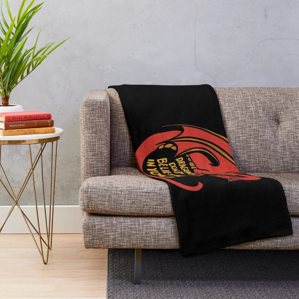 A plush red dragon-themed blanket with the text "Dragons don't believe in you