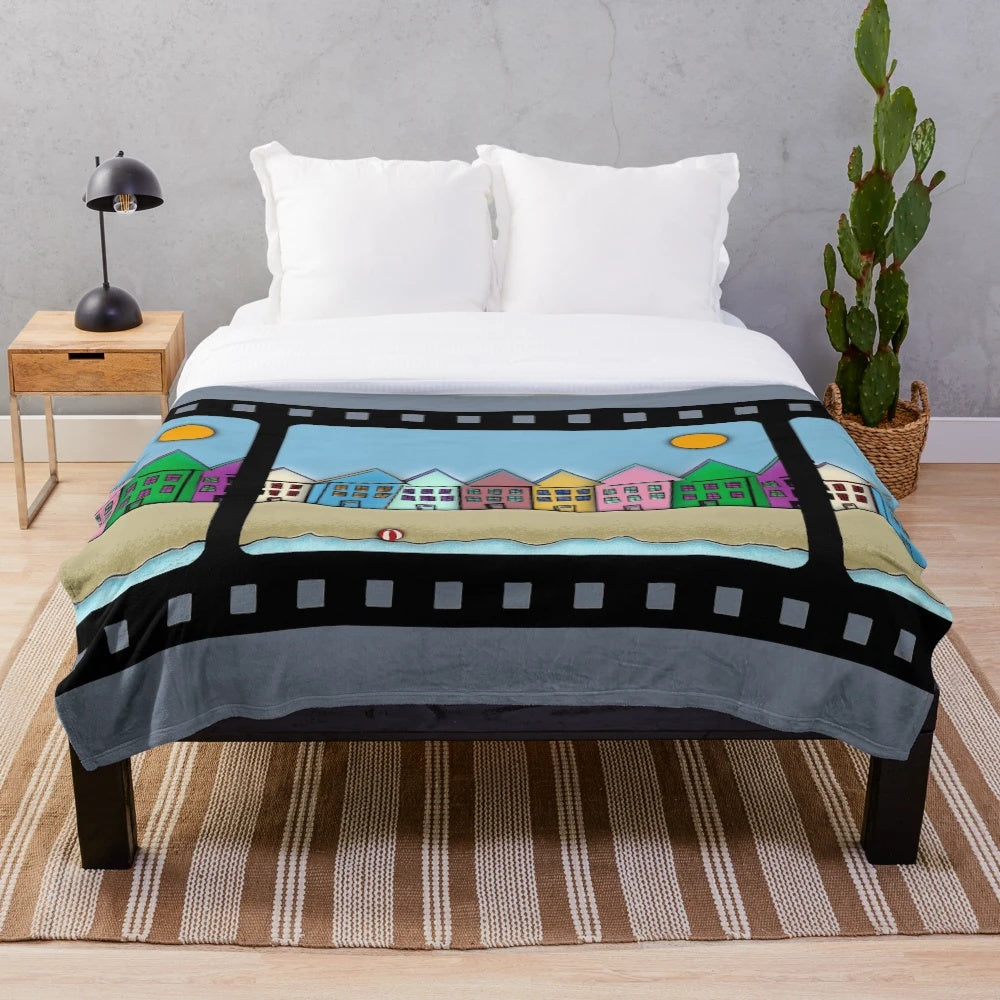 Cozy movie-themed plush blanket featuring digital artwork of houses, sun, beach, and cinema