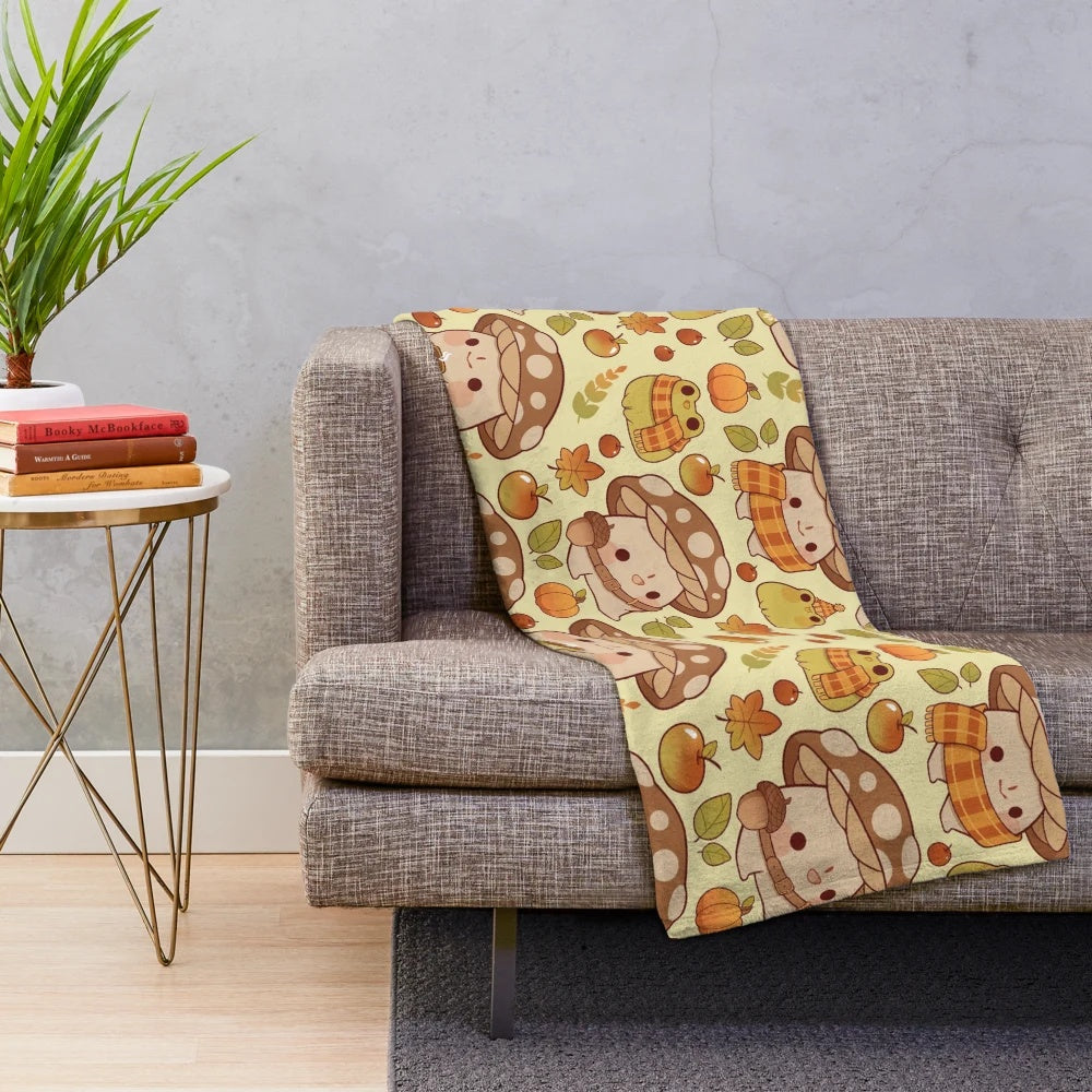 Plush blanket with whimsical mushroom and frog pattern in fall colors