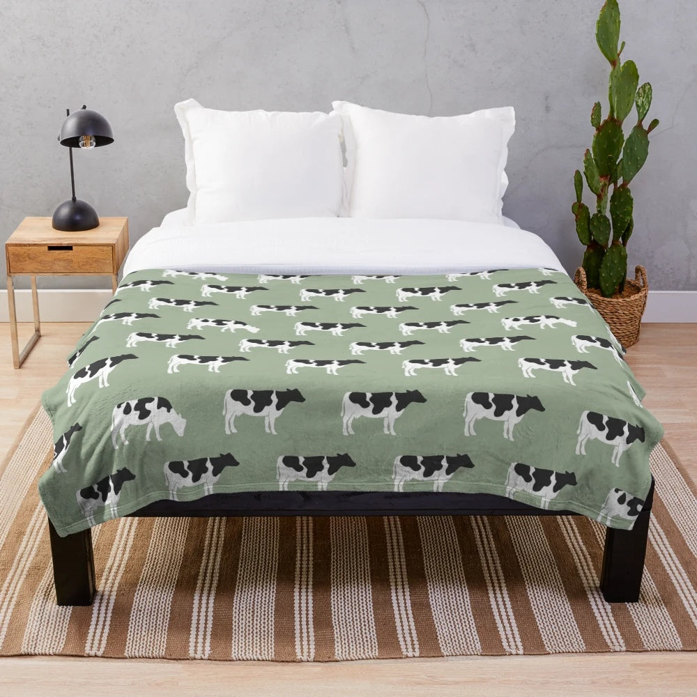 Plush blanket featuring dairy cows against a sage green background