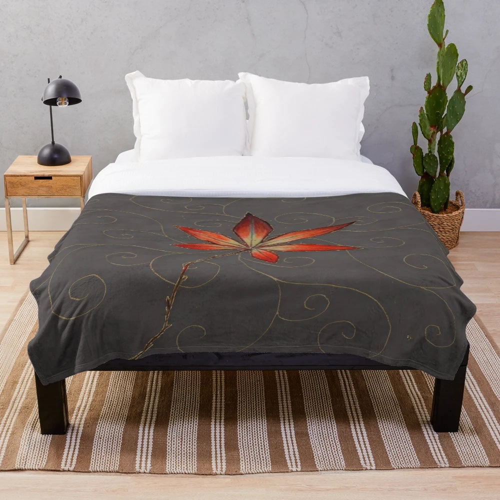 Plush blanket featuring a maple leaf design with gold filigree on a gray background