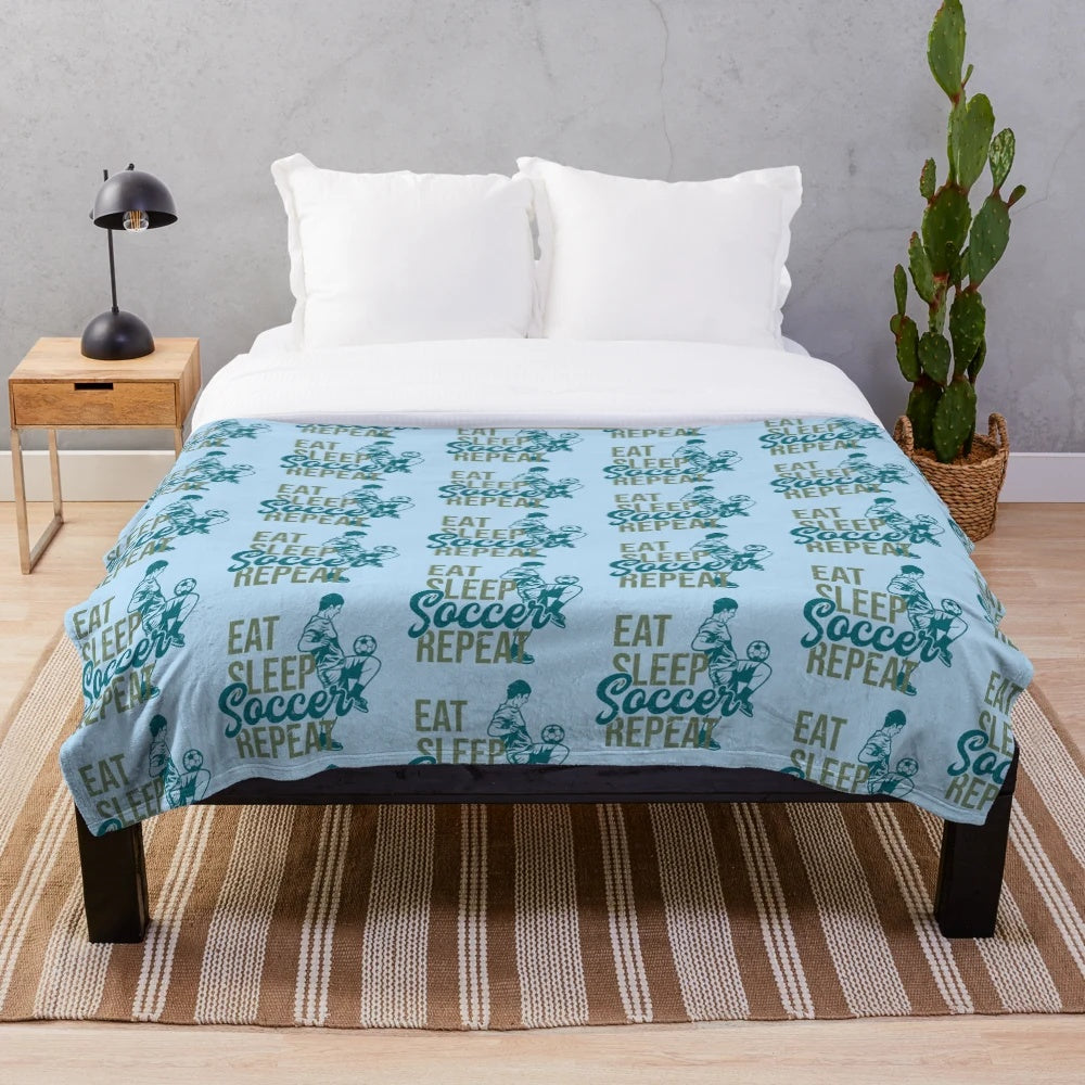 Plush soccer-themed blanket with "Eat Sleep Soccer Repeat" design