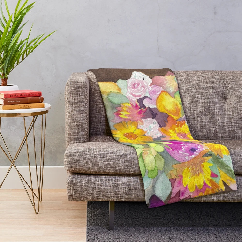 Watercolor painting of a pumpkin and floral bouquet on a soft, plush blanket