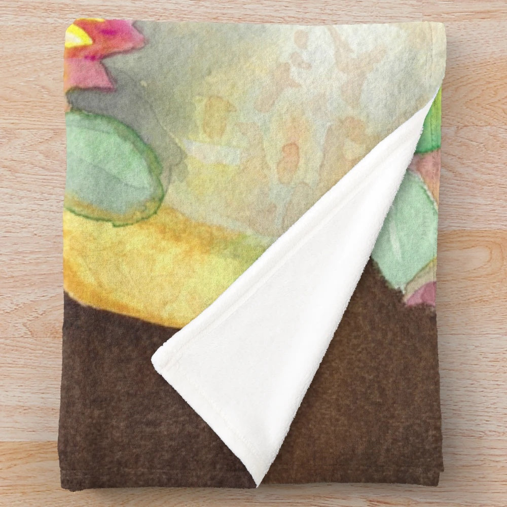 Watercolor painting of a pumpkin and floral bouquet on a soft, plush blanket