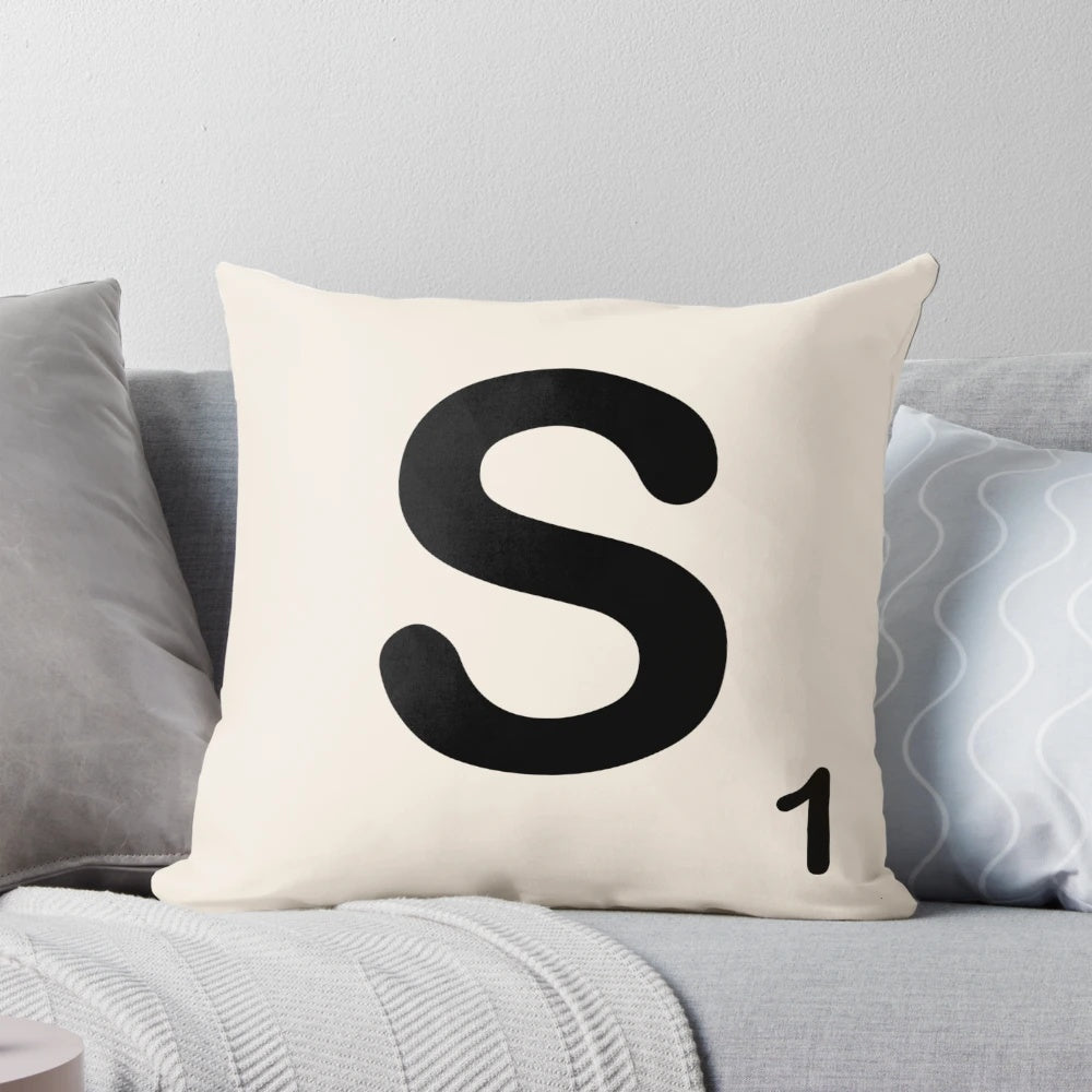 A decorative pillow featuring a stylized Scrabble letter 'S' in a modern, minimalist design.