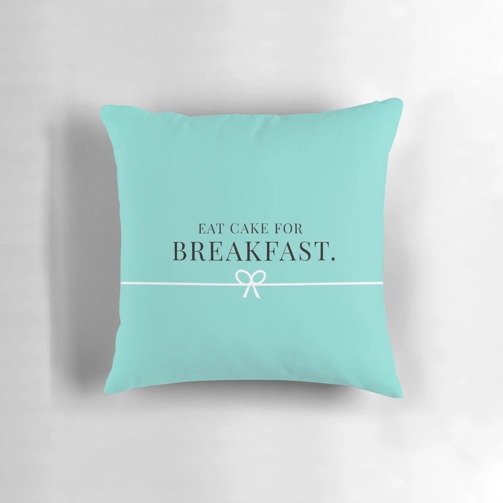 Two pink and teal pillows with a breakfast-themed design, featuring donuts, cakes, and Tiffany-style branding.