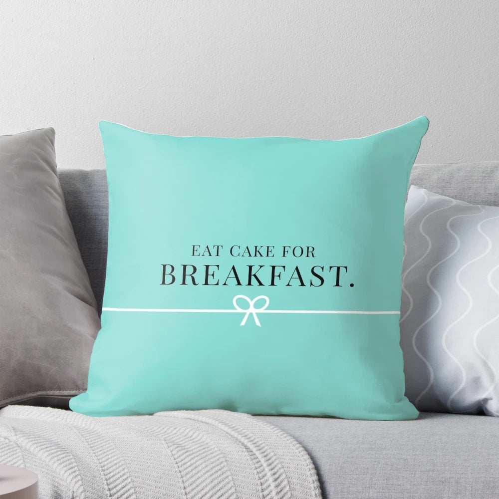 Two pink and teal pillows with a breakfast-themed design, featuring donuts, cakes, and Tiffany-style branding.