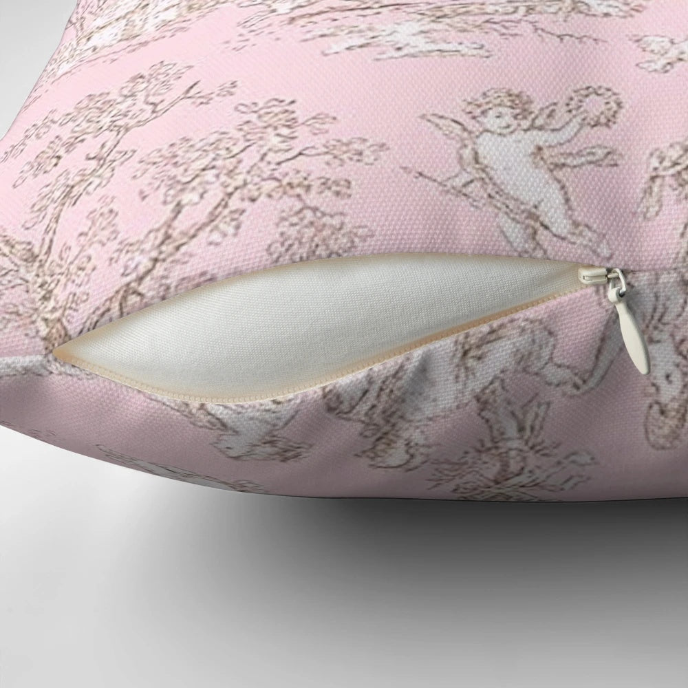 A pink and white toile patterned pillow with a French country design featuring birds and branches.