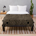Greek key meander pattern printed on a black and gold plush blanket