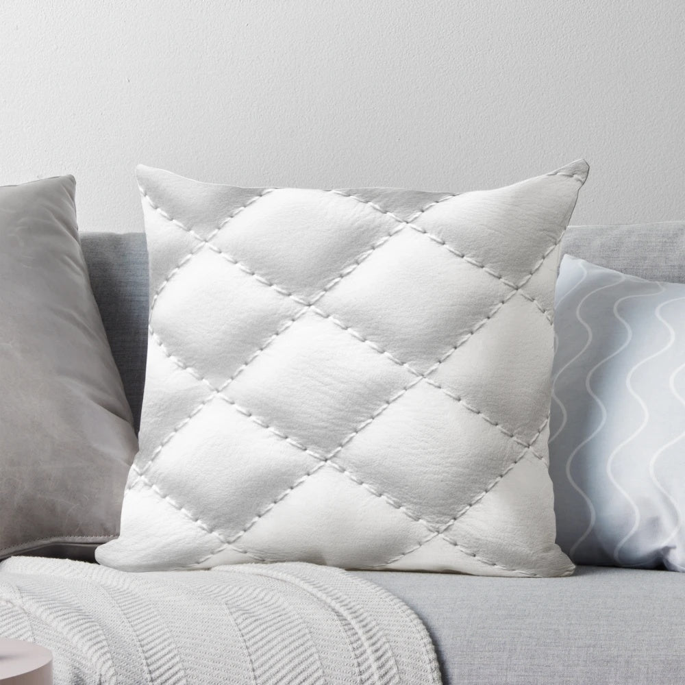 Closeup of a white, quilted leather-effect pillow with a plush, textured surface.