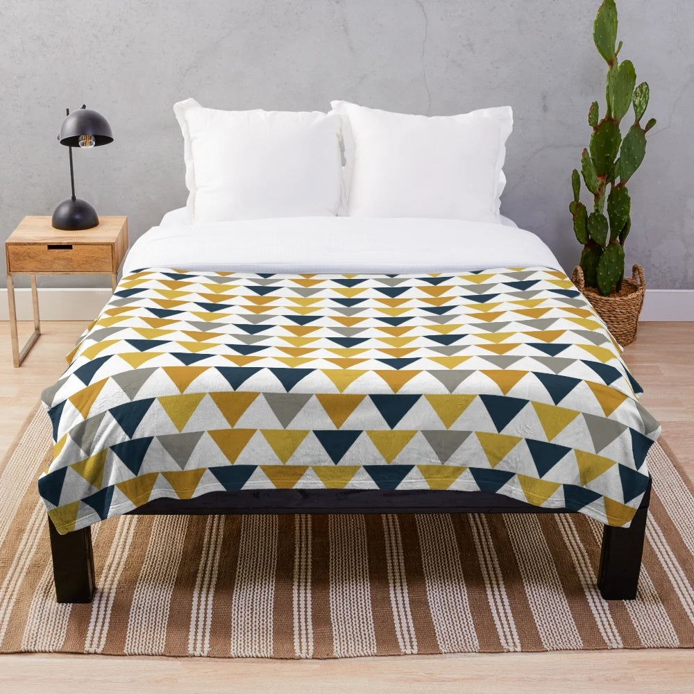 Geometric pattern plush blanket in mustard yellow, dark blue, and gray colors
