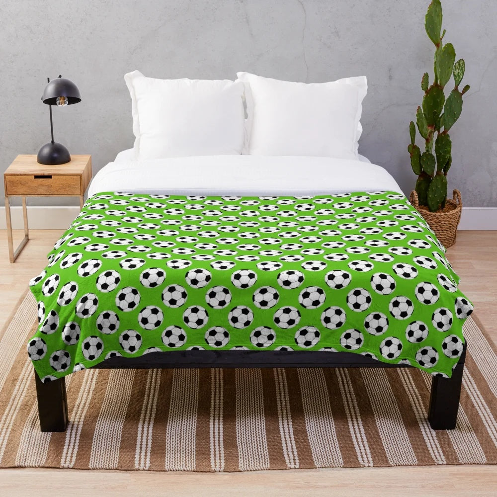 Green plush blanket with a black and white soccer ball pattern