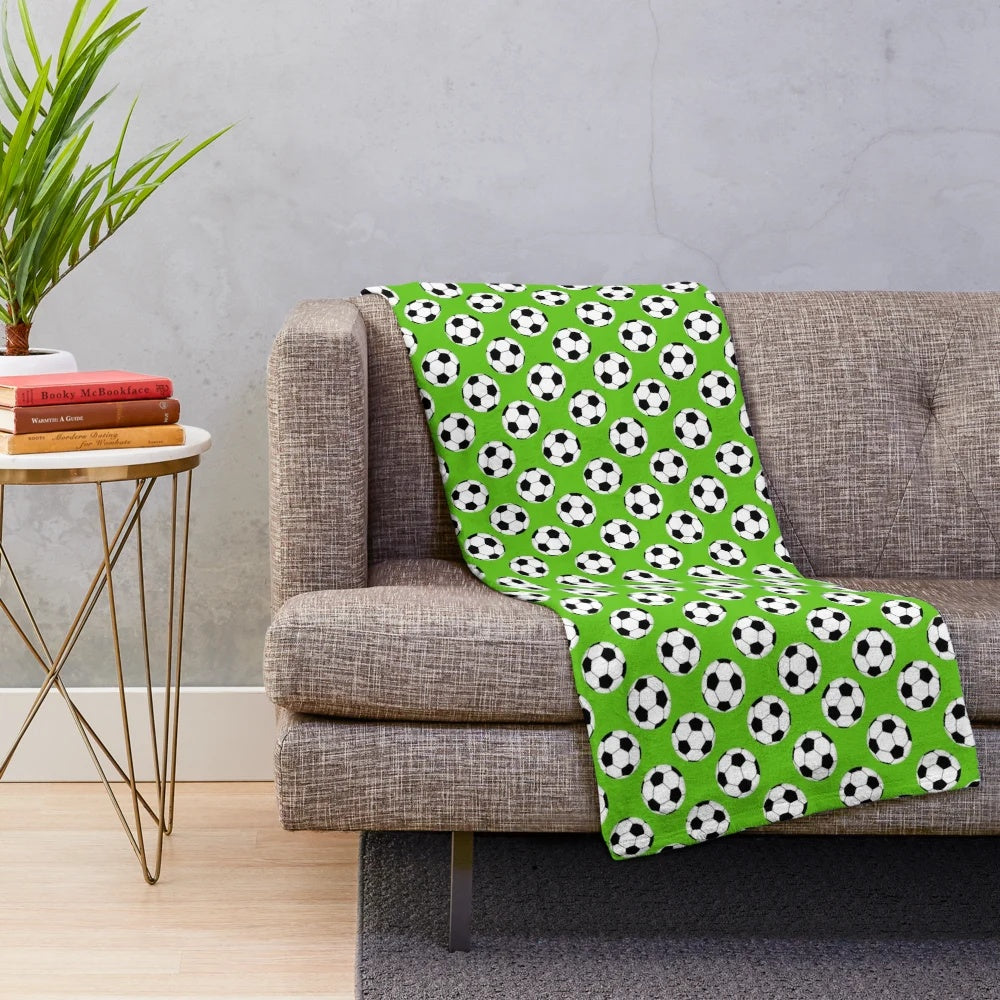 Green plush blanket with a black and white soccer ball pattern