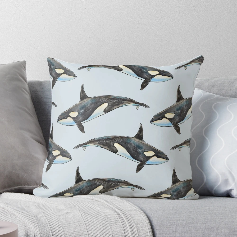 A beautifully hand-painted watercolor illustration of an orca whale on a blue background, featured on a decorative pillow.