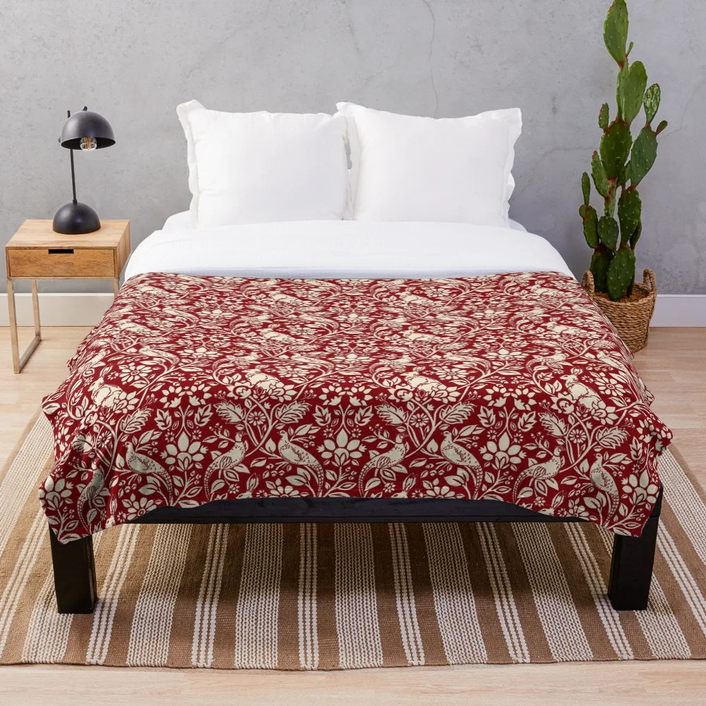 Plush blanket with a vintage-inspired pheasant and hare pattern in deep red and cream colors