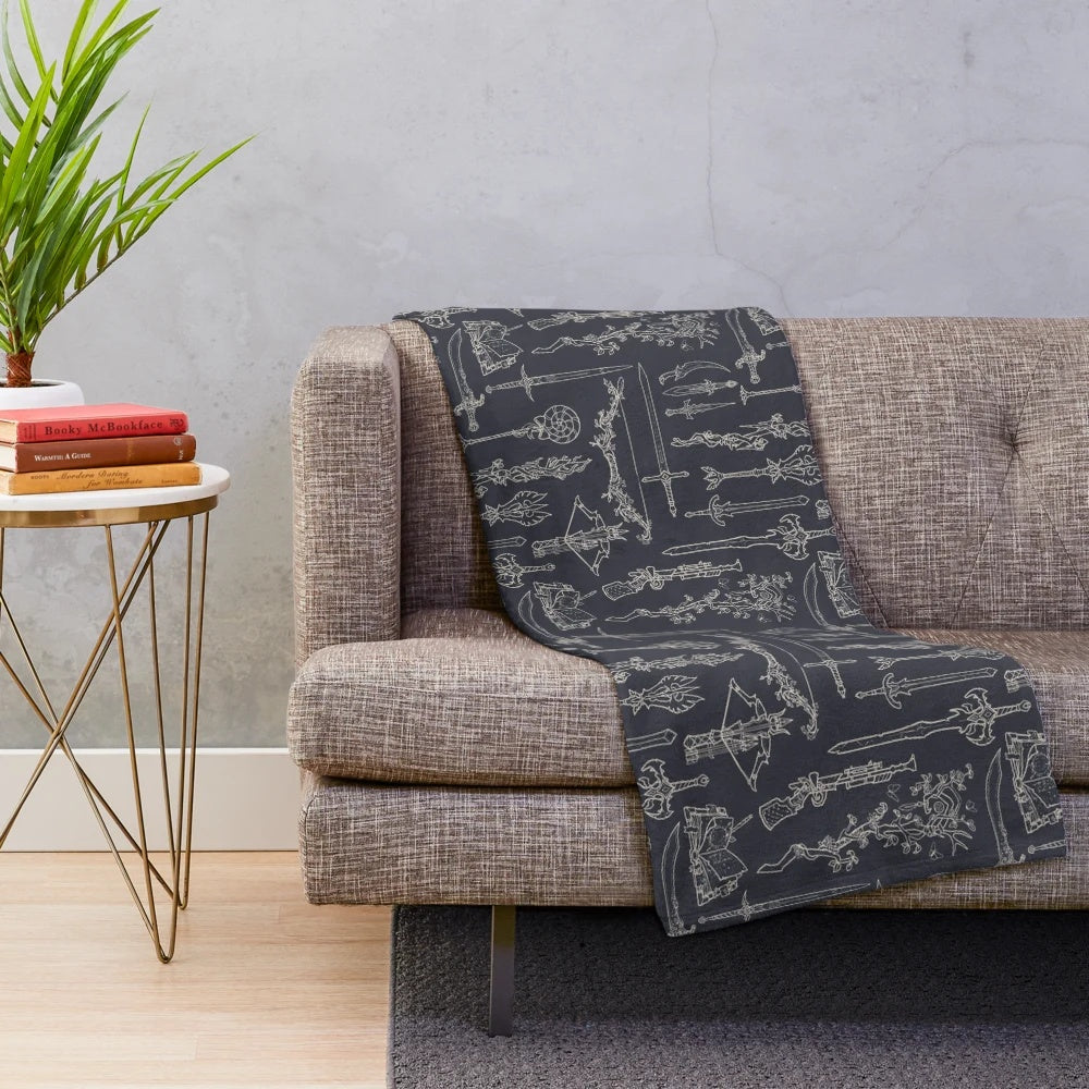 Plush blanket featuring illustrated fantasy weapons like swords, daggers, and wands for tabletop RPG enthusiasts.