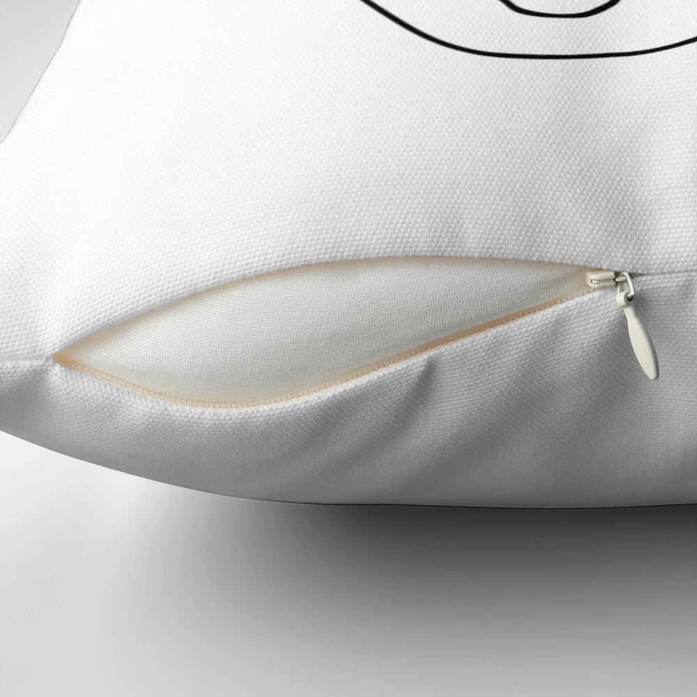 A black and white minimalist throw pillow featuring a simple, continuous line drawing of a face.