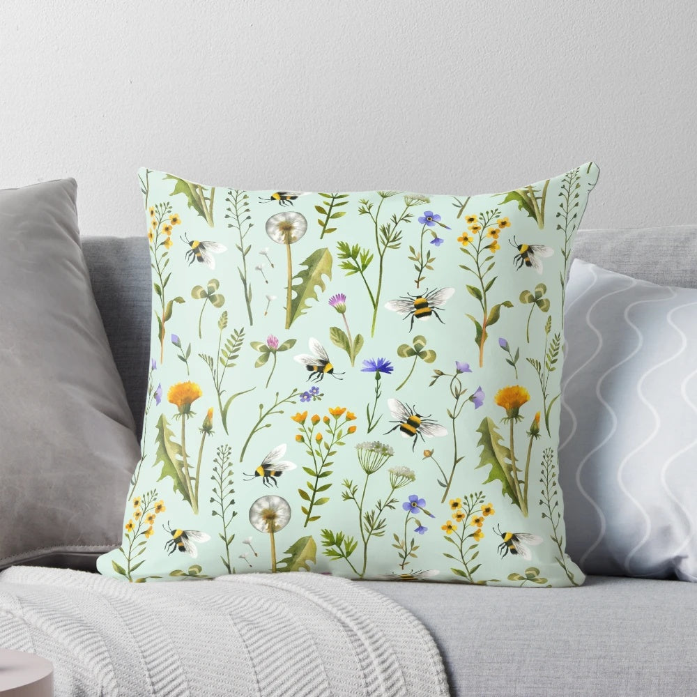 Mint-colored pillow with a design featuring bees, wildflowers, and botanicals