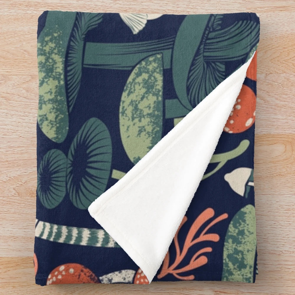 Mystical fungi patterned plush blanket with midnight blue, sage green, forest green, and orange wild mushrooms