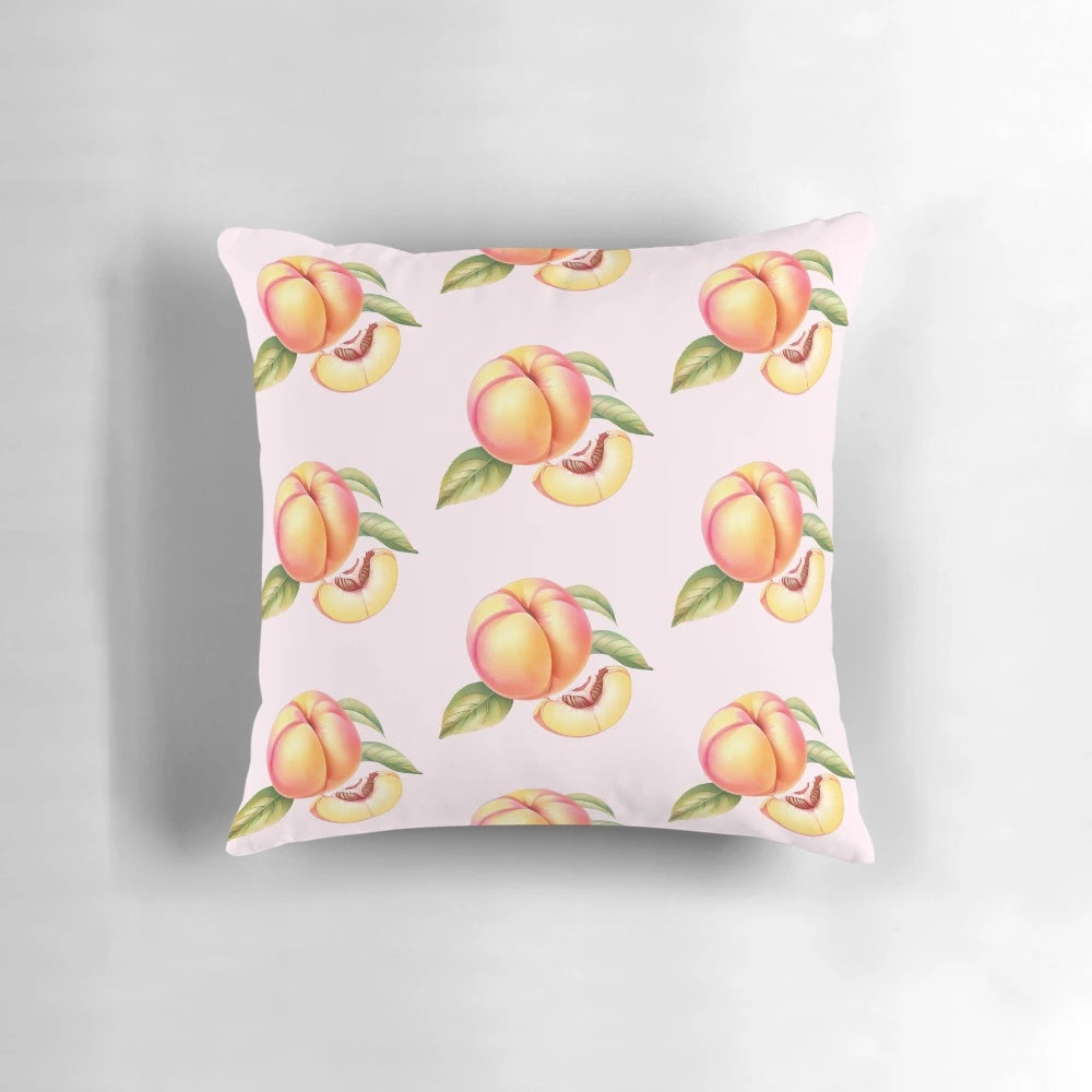 Peach pillow with leaves and a slice of peach on a white background