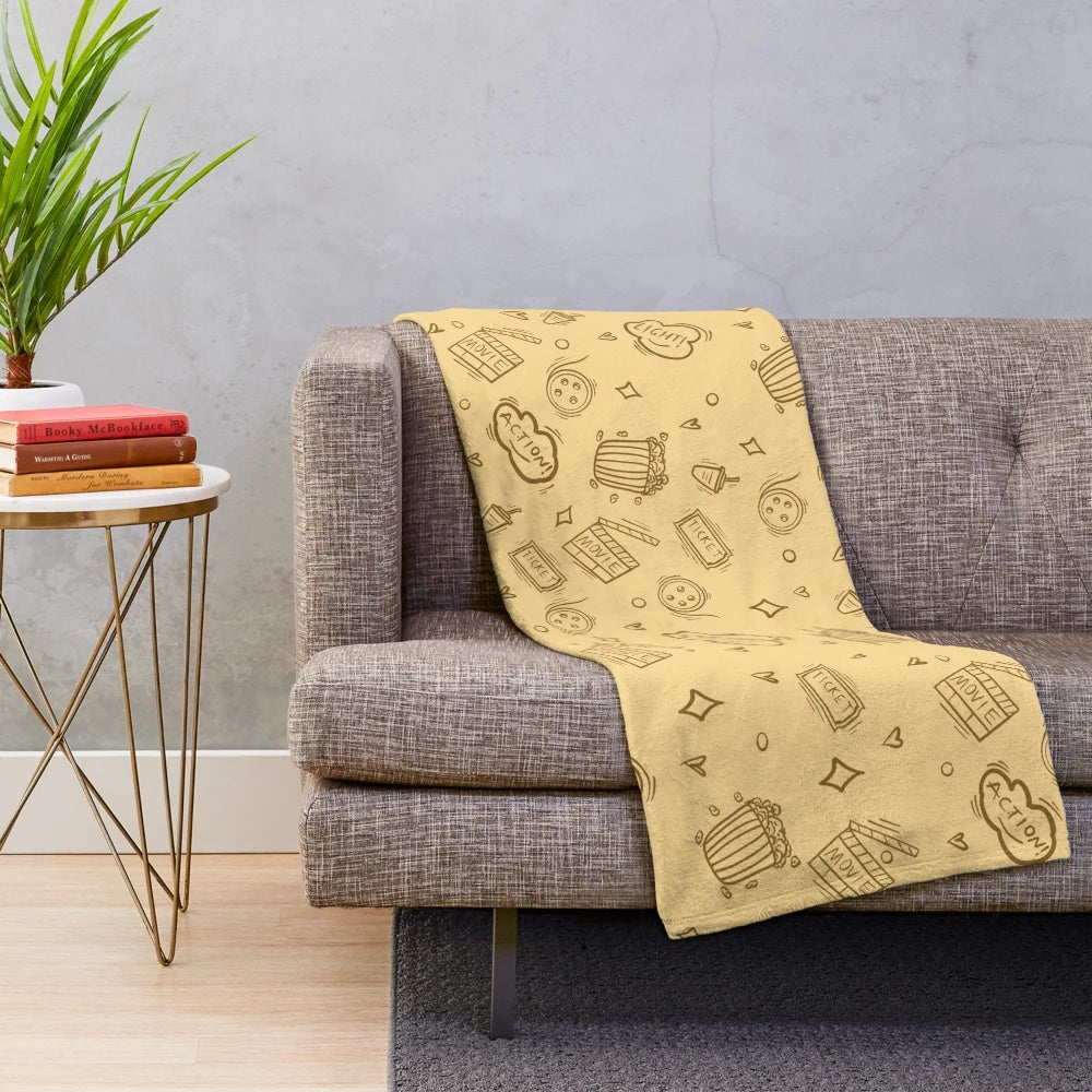 Plush blanket with a retro cinema-inspired pattern featuring movie elements like popcorn, cameras, and classic drinks.