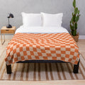 Cozy plush blanket with a vibrant orange checkered and wavy pattern, featuring a retro geometric design
