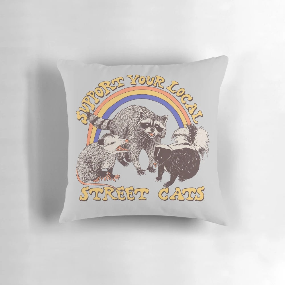 A colorful retro-style pillow featuring a design of street cats, possums, skunks, and raccoons in a vintage 80s style.