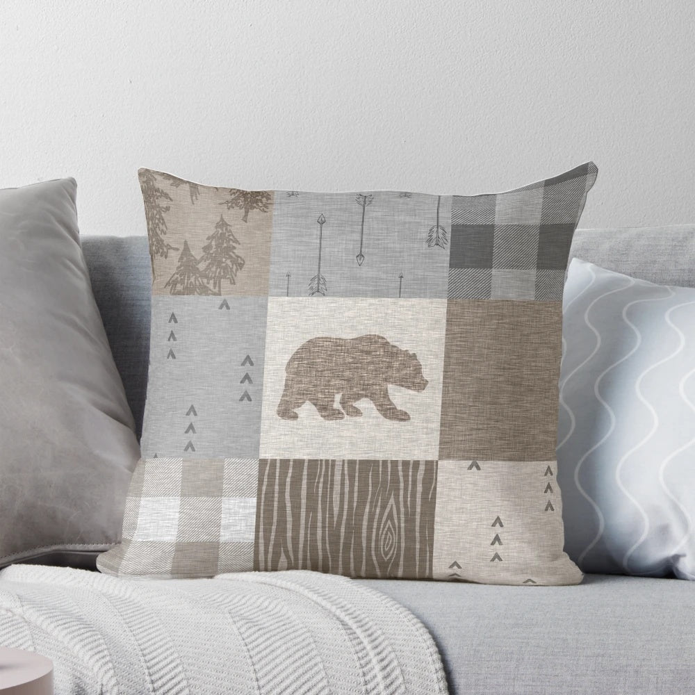 A rustic patchwork pillow in neutral tones featuring a bear design, perfect for woodland and camping themed home decor.