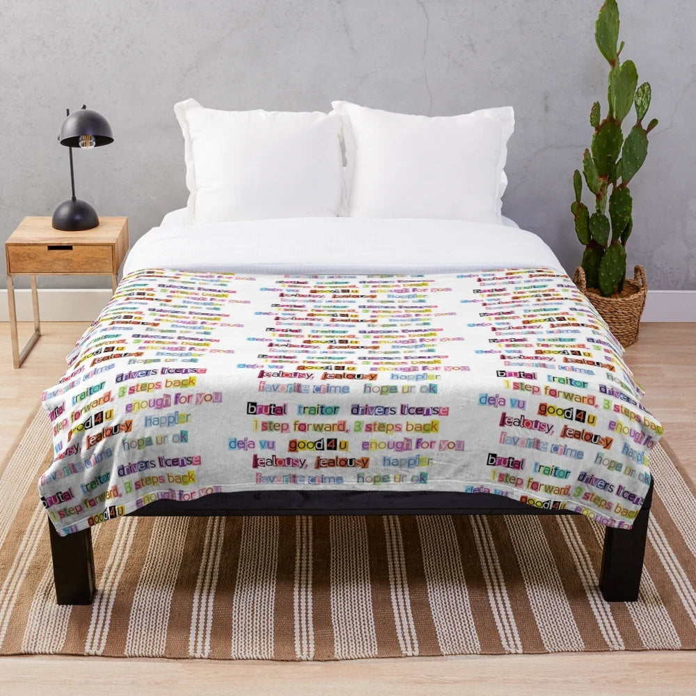 Soft plush blanket decorated with song titles from Olivia Rodrigo's album Sour