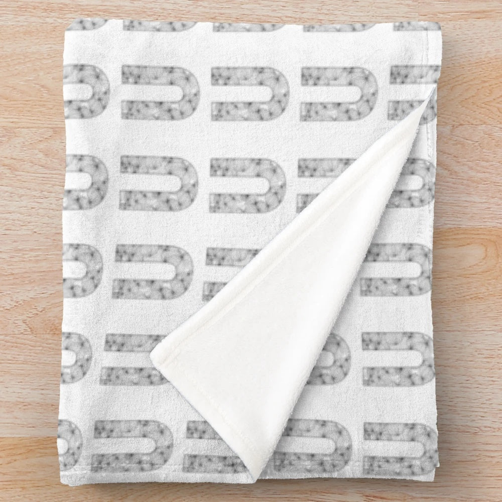 Plush black and white blanket with a stylized letter U pattern