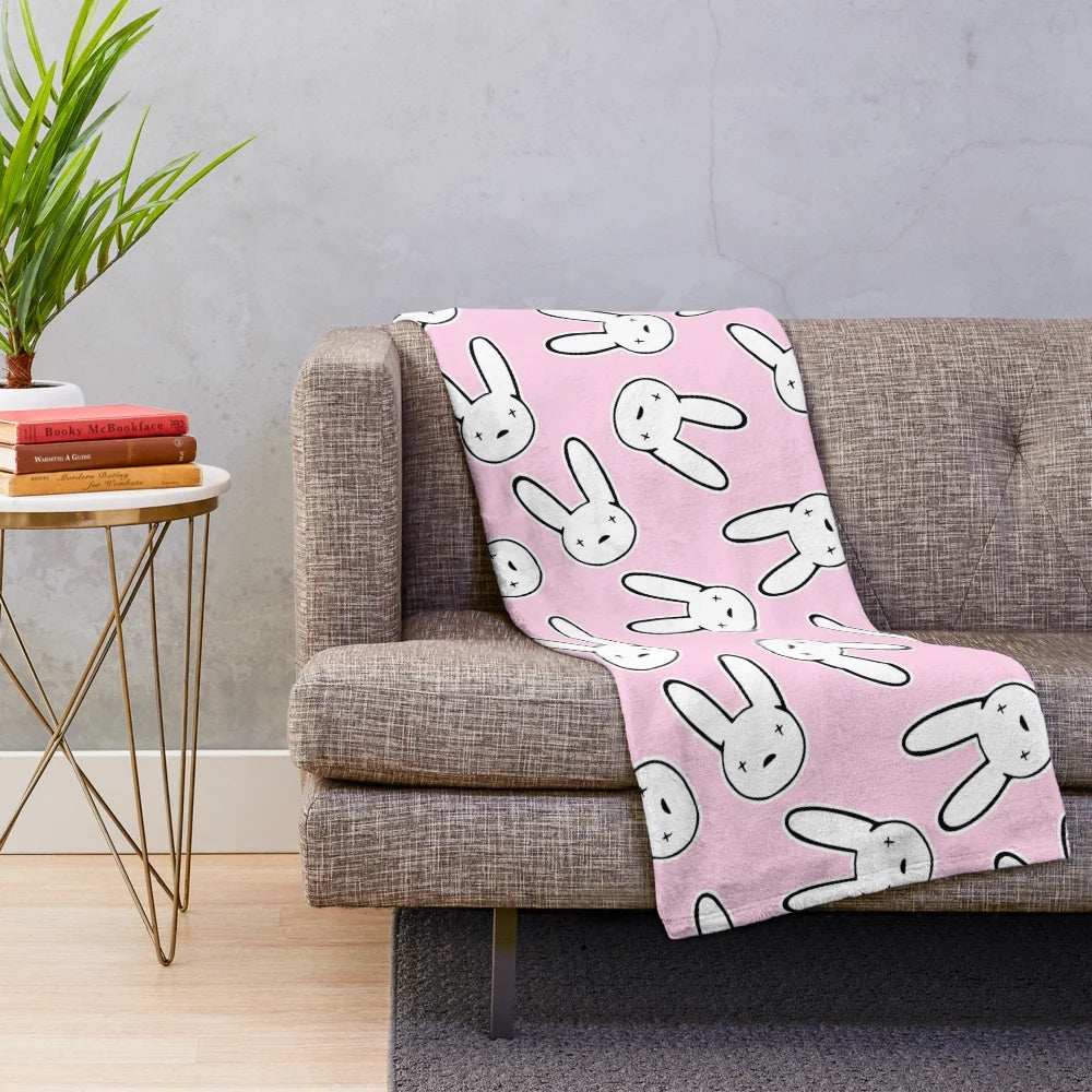 Millennial pink plush blanket featuring the iconic cross-eyed rabbit design from Bad Bunny's Oasis logo