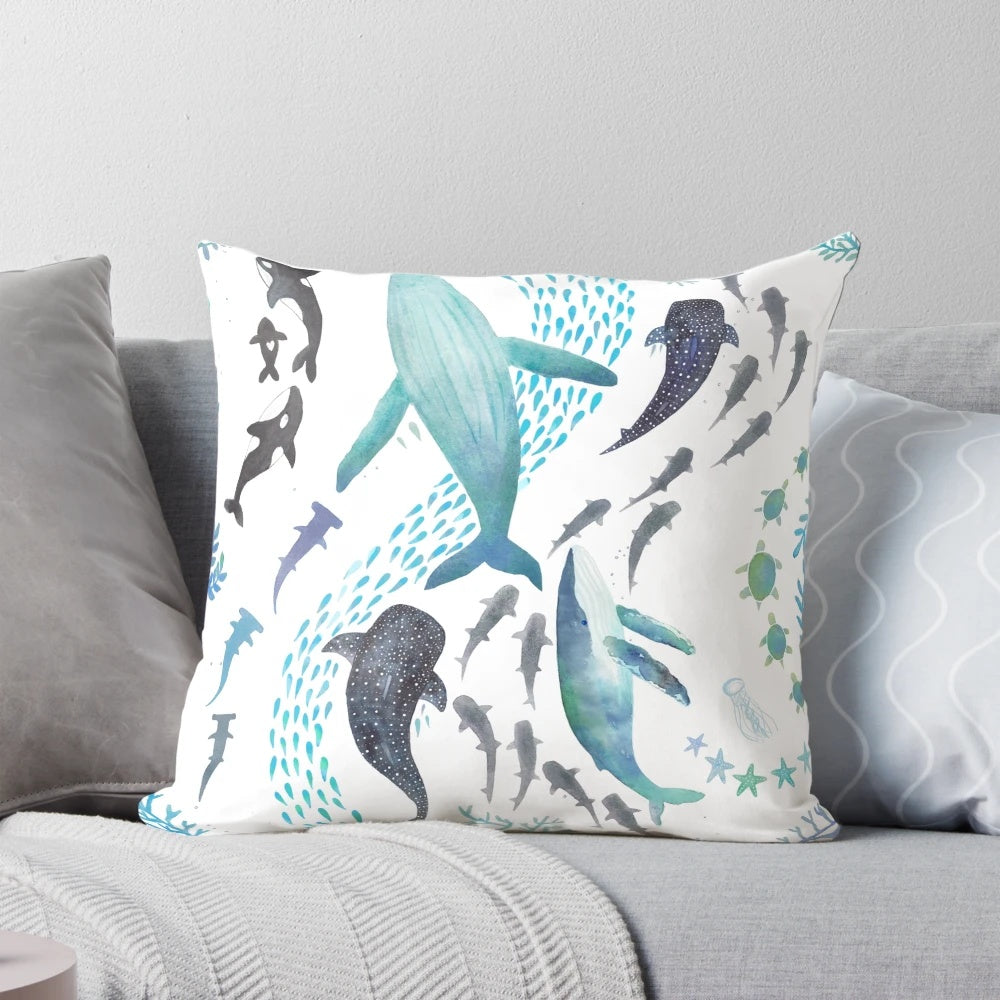 Colorful throw pillow featuring a watercolor design of sharks, whales, orcas, and sea turtles swimming in the ocean.